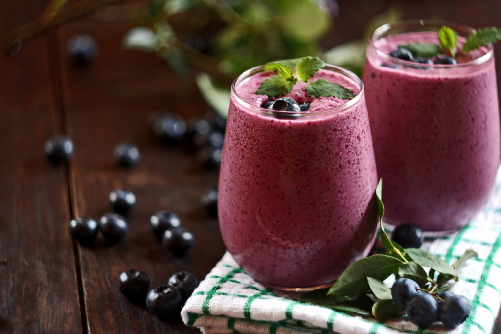 Two glasses of blueberry smoothie on wooden background. Selective focus