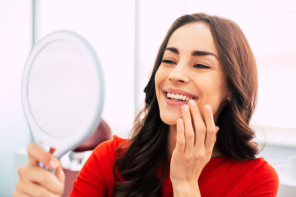 woman looking at her smile in a mirror