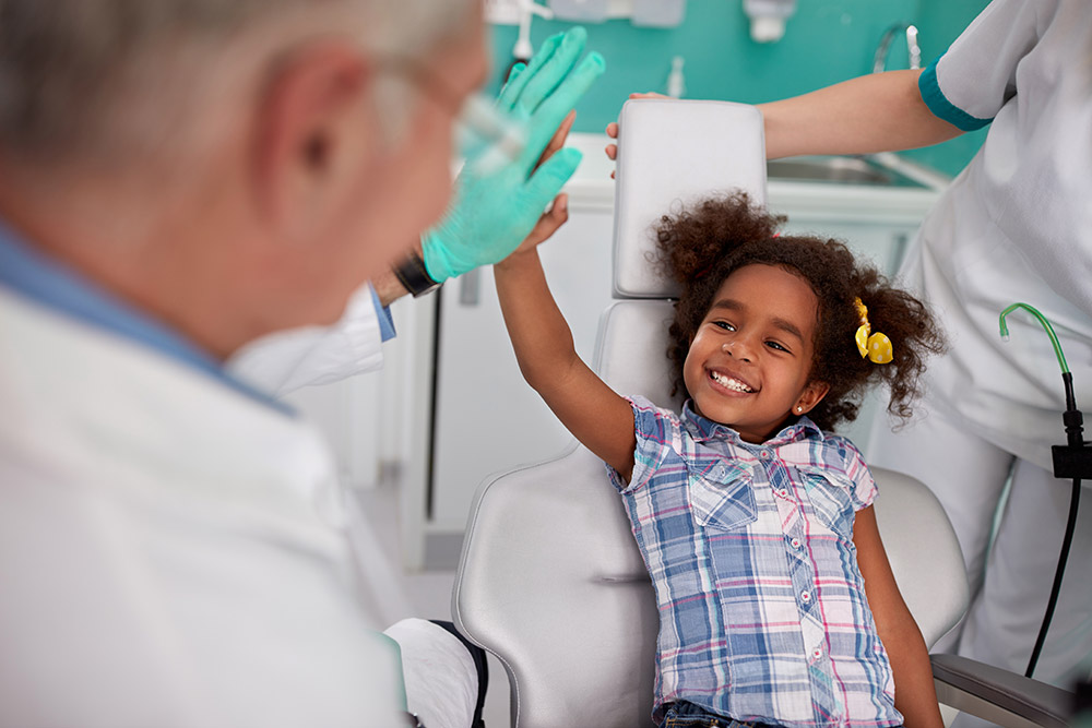 little girl smiling in a dentist chair