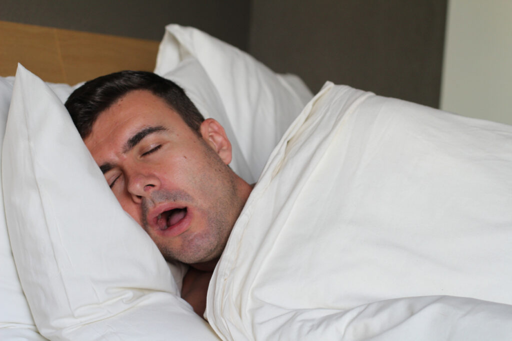 A person sleeps deeply with their mouth open.