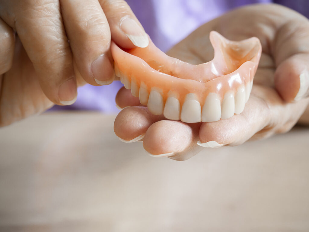 Hands displaying a fresh set of dentures.